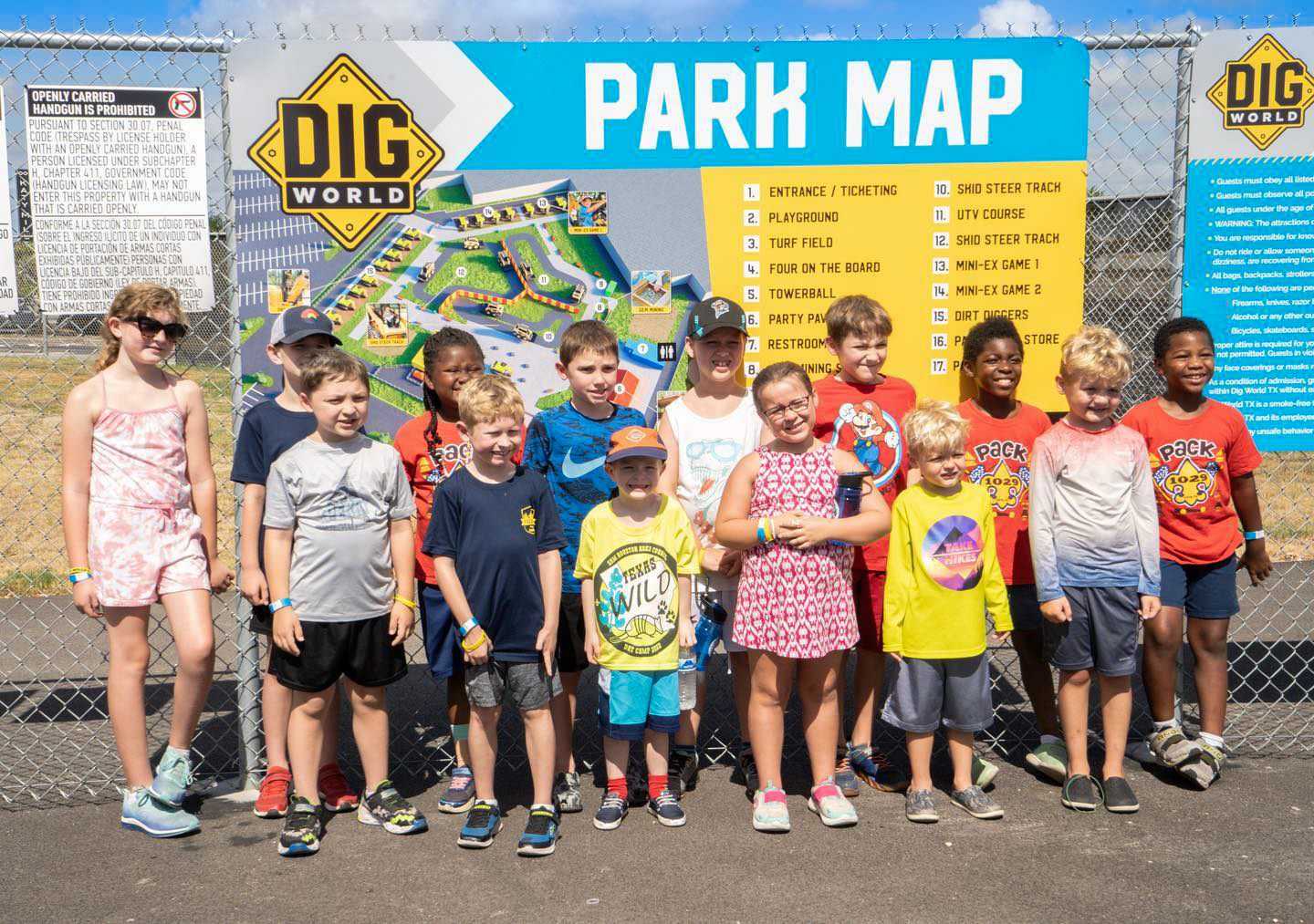 A group of children gathered in front of the Dig World Katy park map.