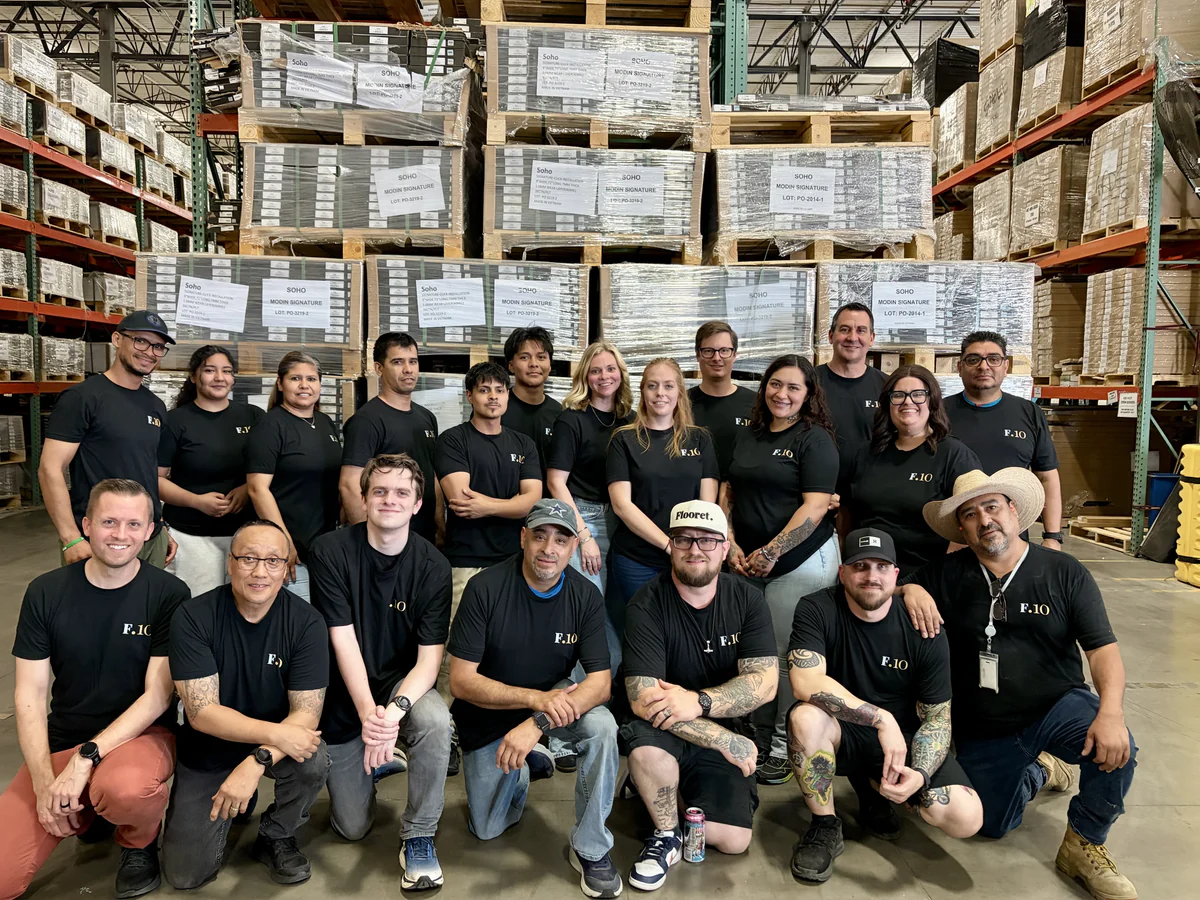 A team photo of Flooret personnel in matching black shirts inside a warehouse