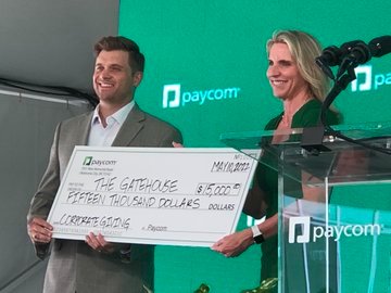 A.J. Griffin (right) of Paycom presents a donation to The Gatehouse during the company's grand opening.