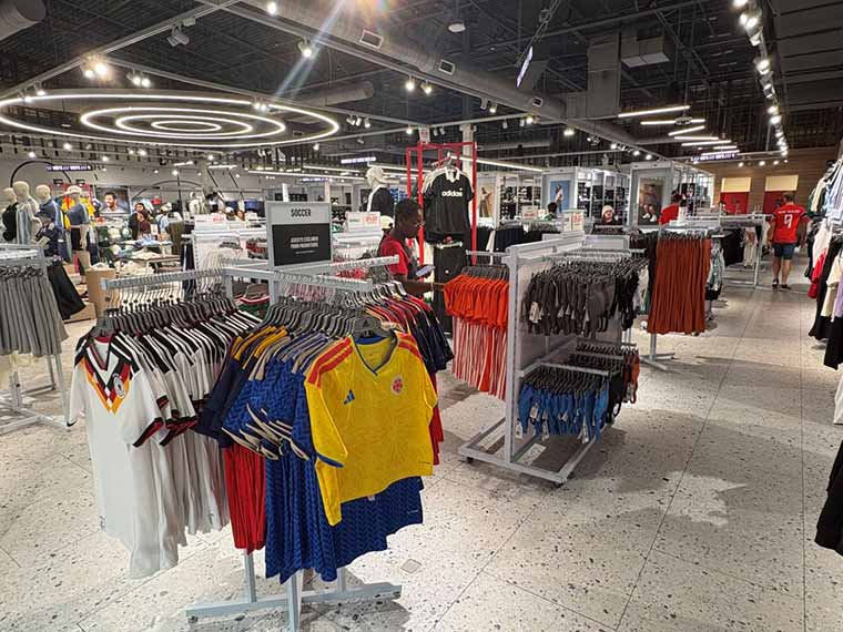 A bright sports apparel store featuring colorful soccer jerseys on racks in the foreground
