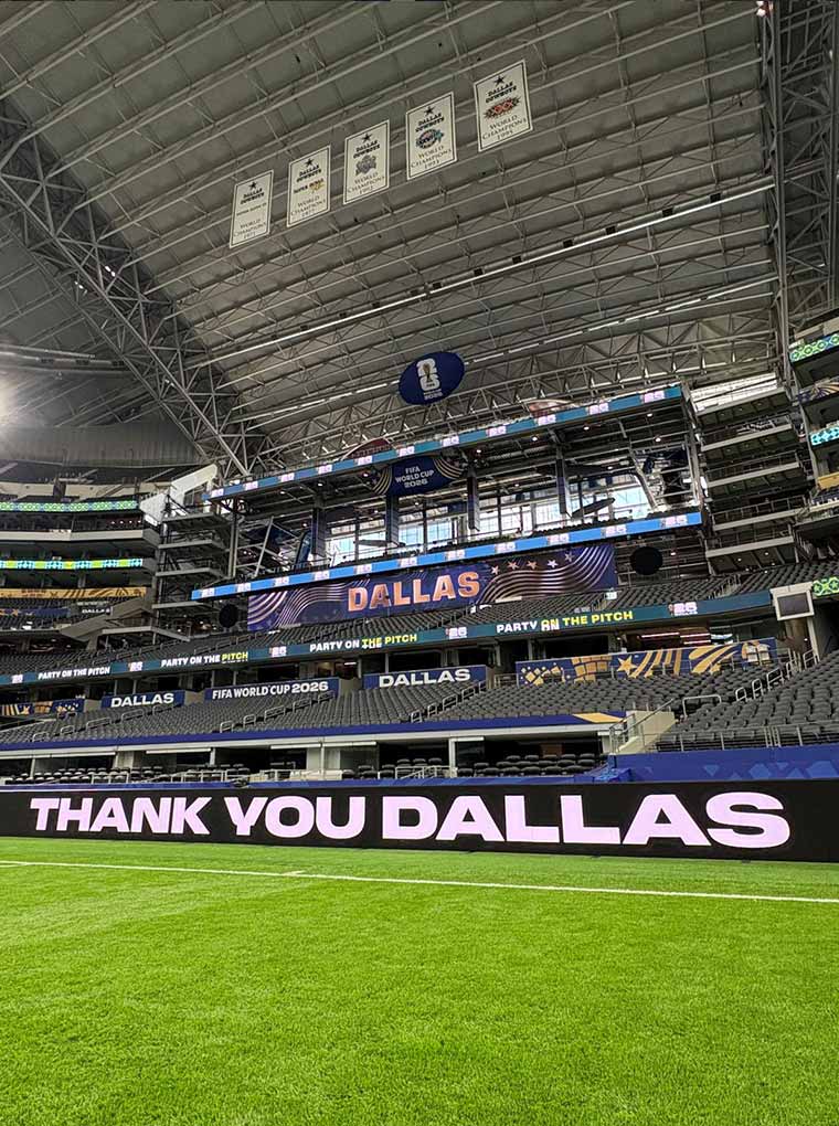 A stadium showing a large grassy field and a banner reading "THANK YOU DALLAS."